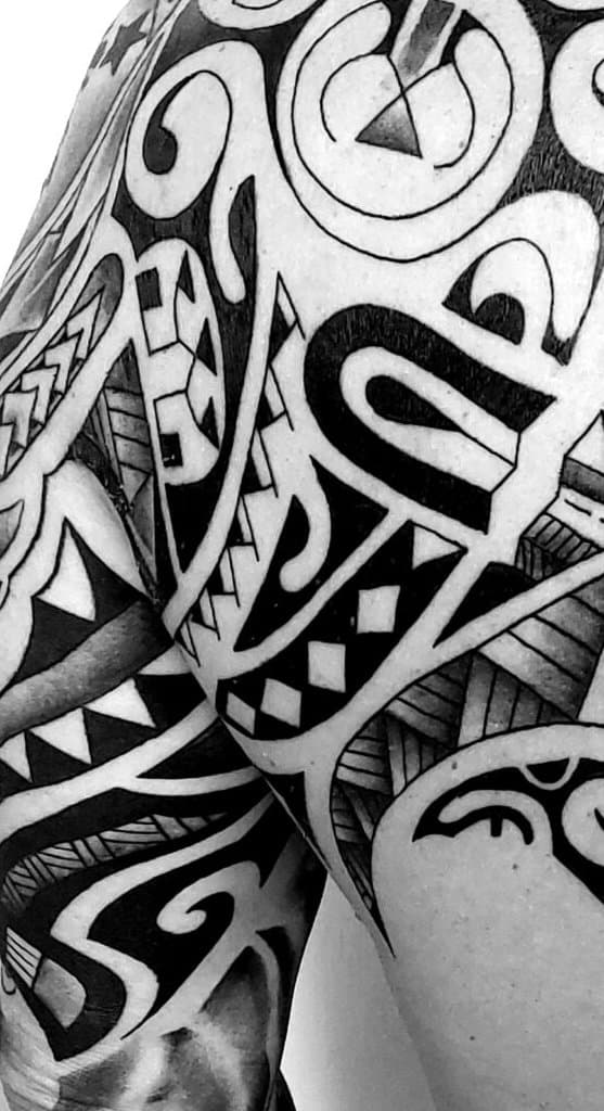 Polynézsky blackwork cez celý chrbát — slnečný disk medzi lopatkami, manta a žralok schádzajúci po chrbtici, ornament pokrýva chrbát až po kríže — detail 3